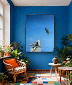 Living room with blue walls, a framed artwork, and decorative plants.