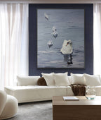Living room with a white sofa, wooden coffee table, and a large framed painting of swans on a blue wall.