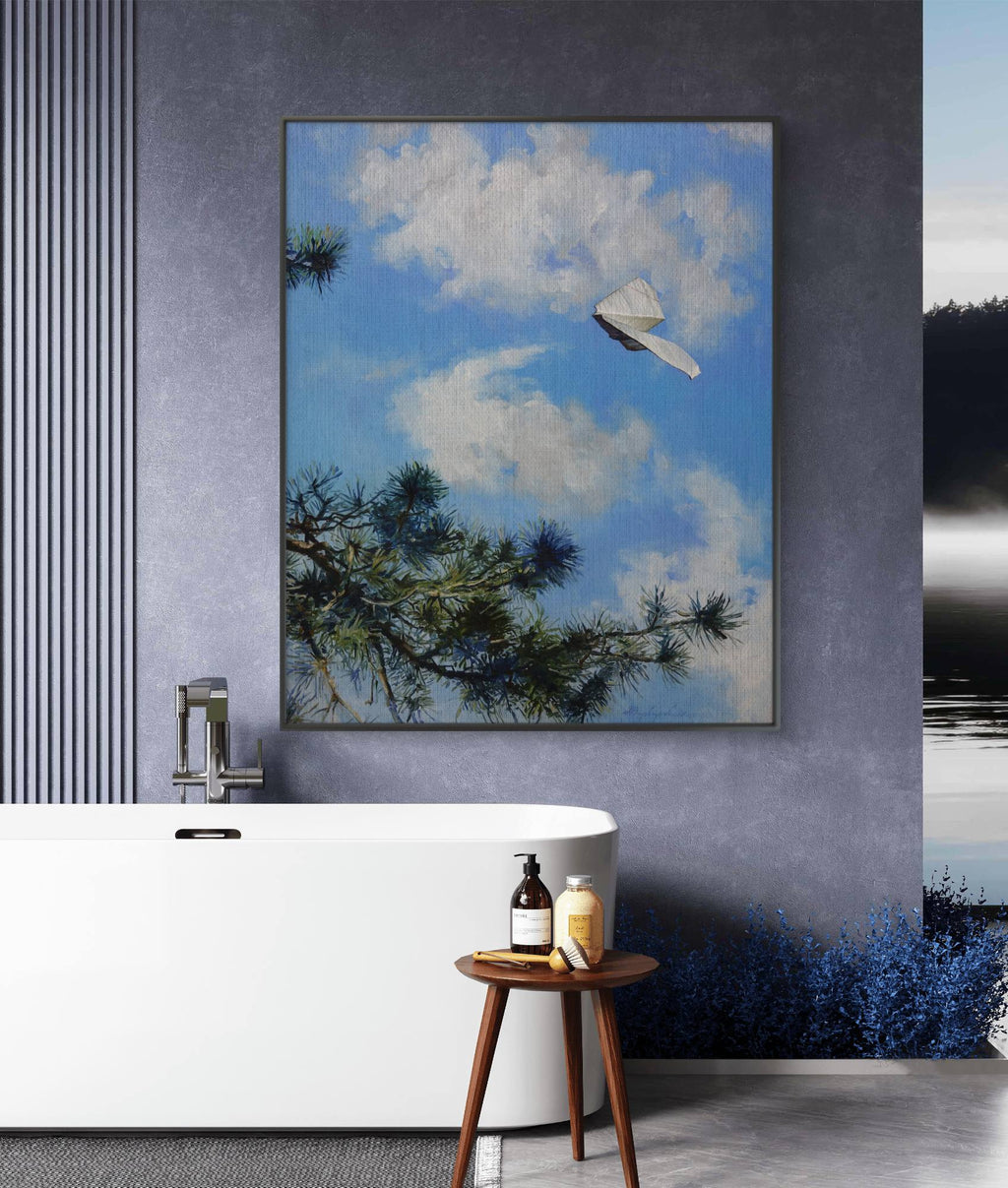 Framed artwork of a blue sky with clouds and tree branches above a bathtub.