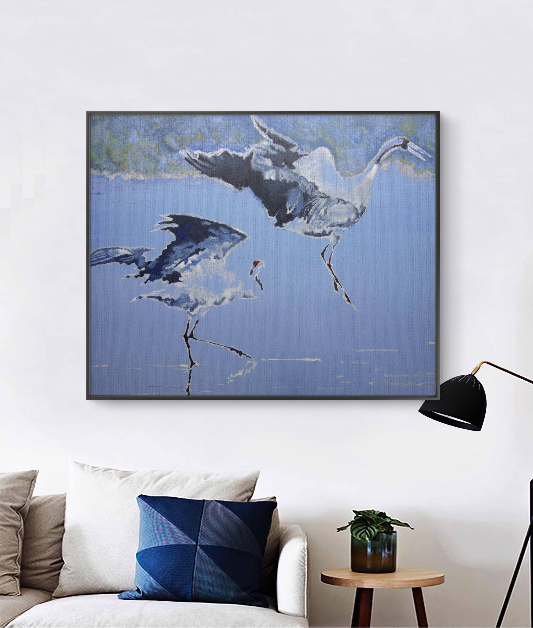 Framed artwork of two birds in flight on a wall above a sofa.