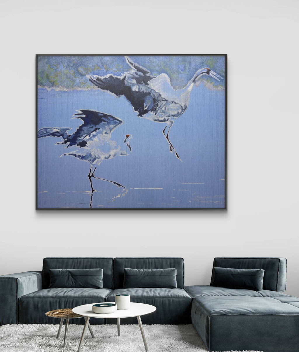 Framed artwork of two birds on a blue background above a gray sectional sofa.