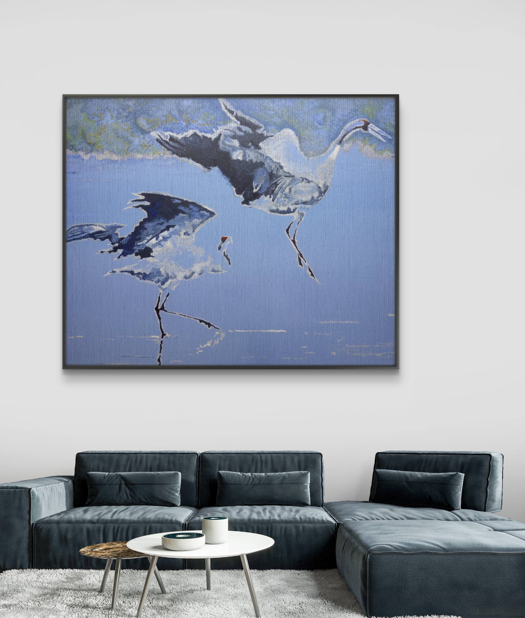 Framed artwork of two birds on a blue background above a gray sectional sofa.