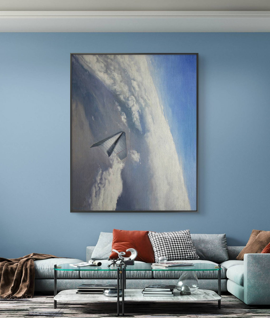 Framed artwork of a mountain landscape with a plane on a blue wall above a sofa.