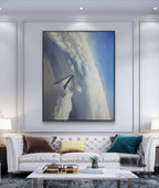Modern living room with a white sofa, coffee table, and large framed artwork on the wall.