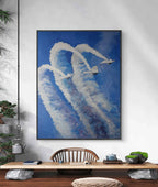 Framed artwork of airplanes leaving smoke trails on a wall above a wooden desk.