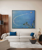 Living room with a white sofa, blue pillows, and a large framed artwork on the wall.