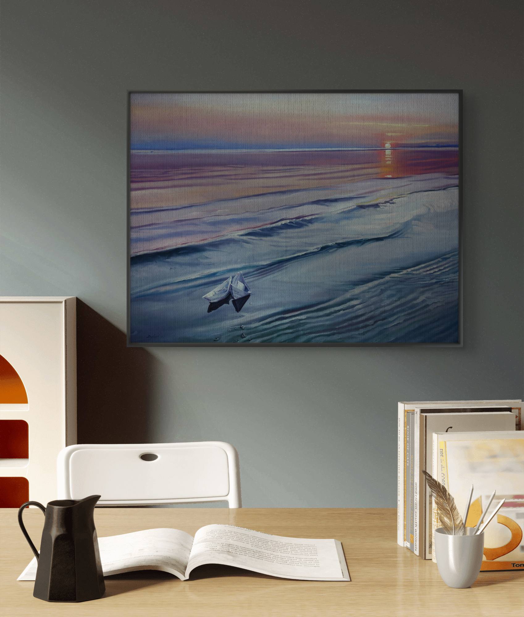 Framed artwork of a beach scene with a lighthouse on a wall above a desk.