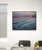 Framed artwork of a boat on water with a sunset or sunrise scene, hanging on a wall above a desk.