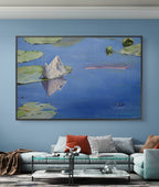 Framed artwork of a water lily painting on a blue wall above a sofa.