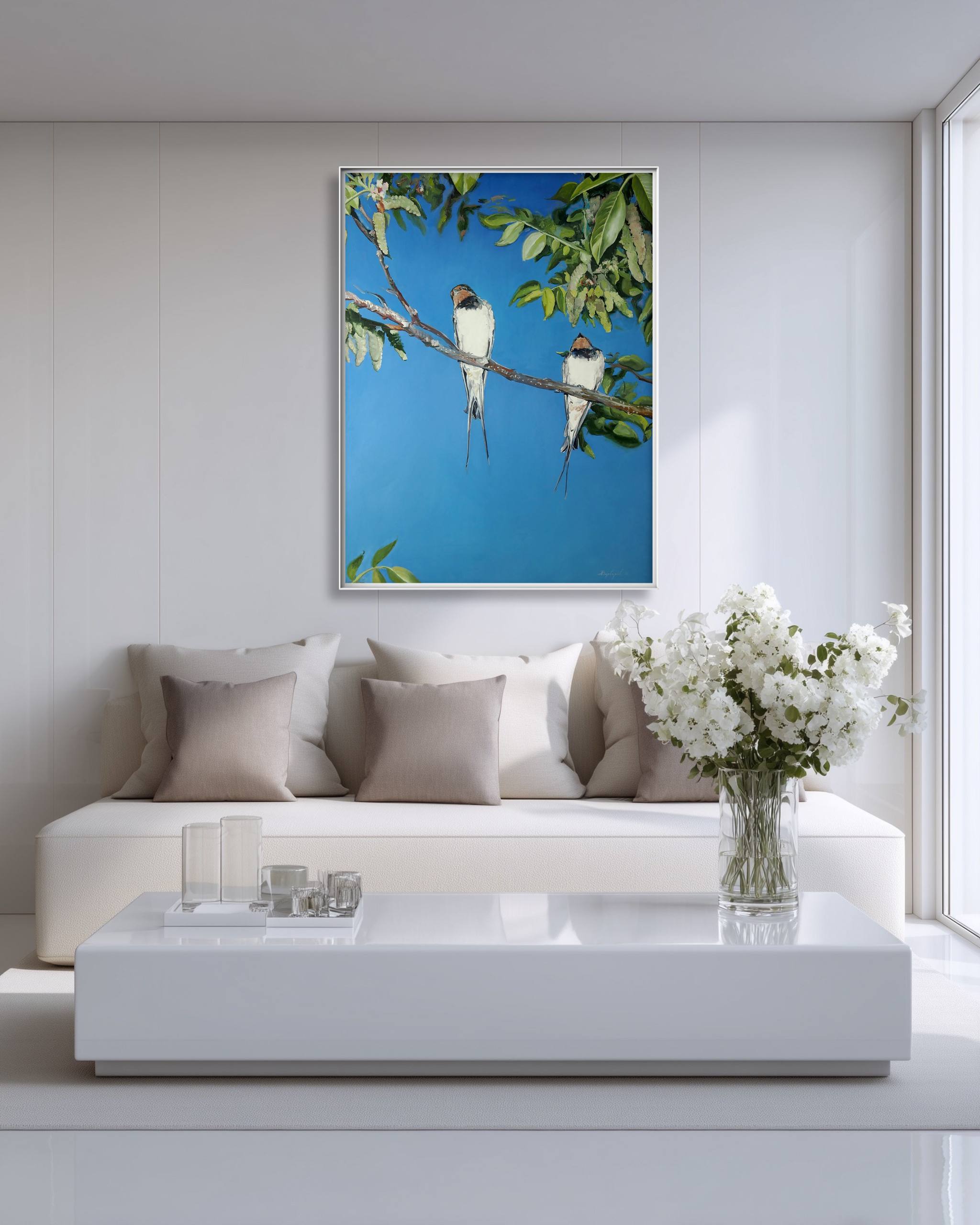 Modern living room with a white sofa, coffee table, and decorative wall art of birds on a branch.