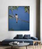 Framed artwork of a bird on a branch above a blue sofa in a living room.