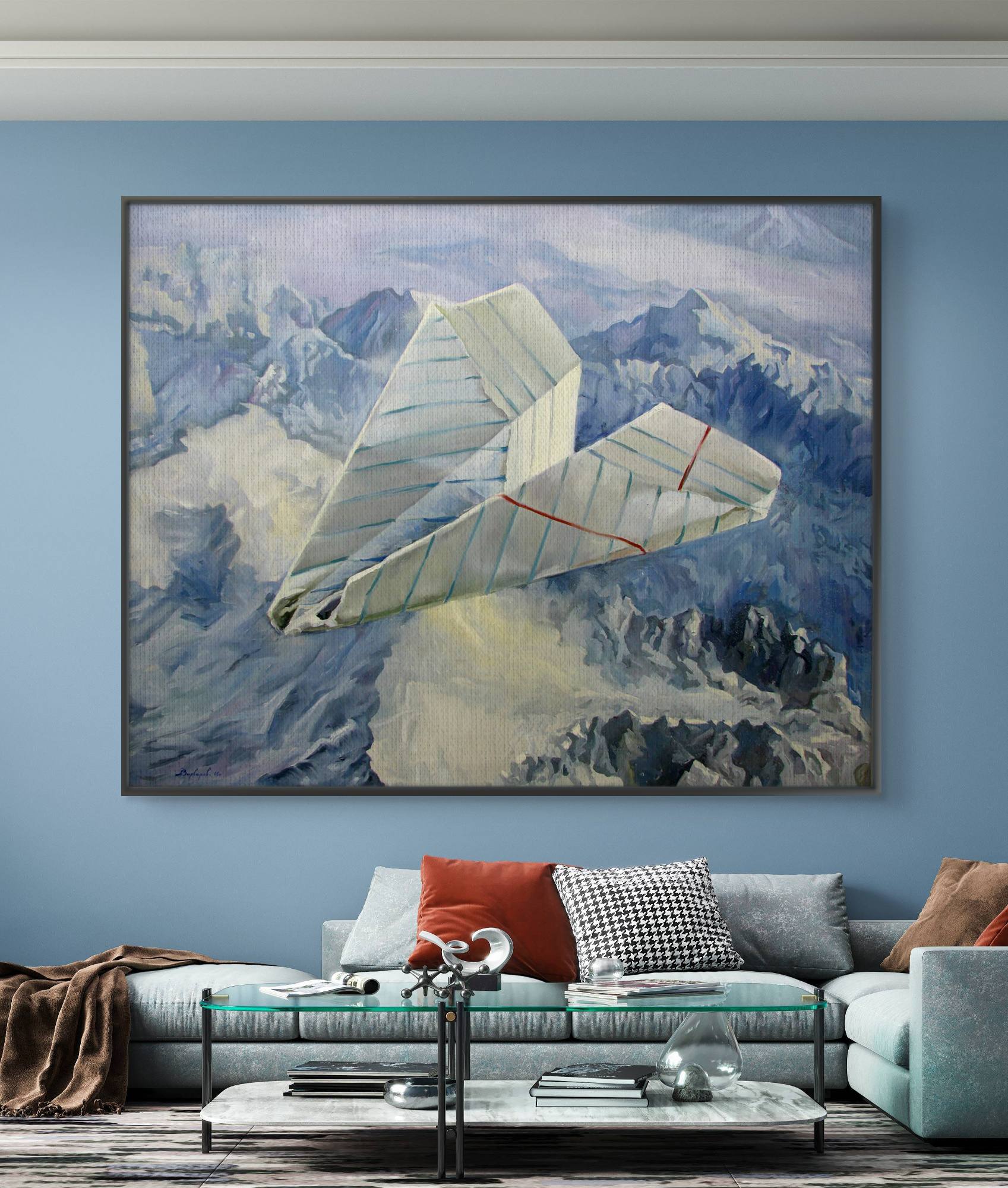 Bedroom with a large framed painting of a paper airplane over mountains, a white sofa with colorful cushions, and a coffee table.