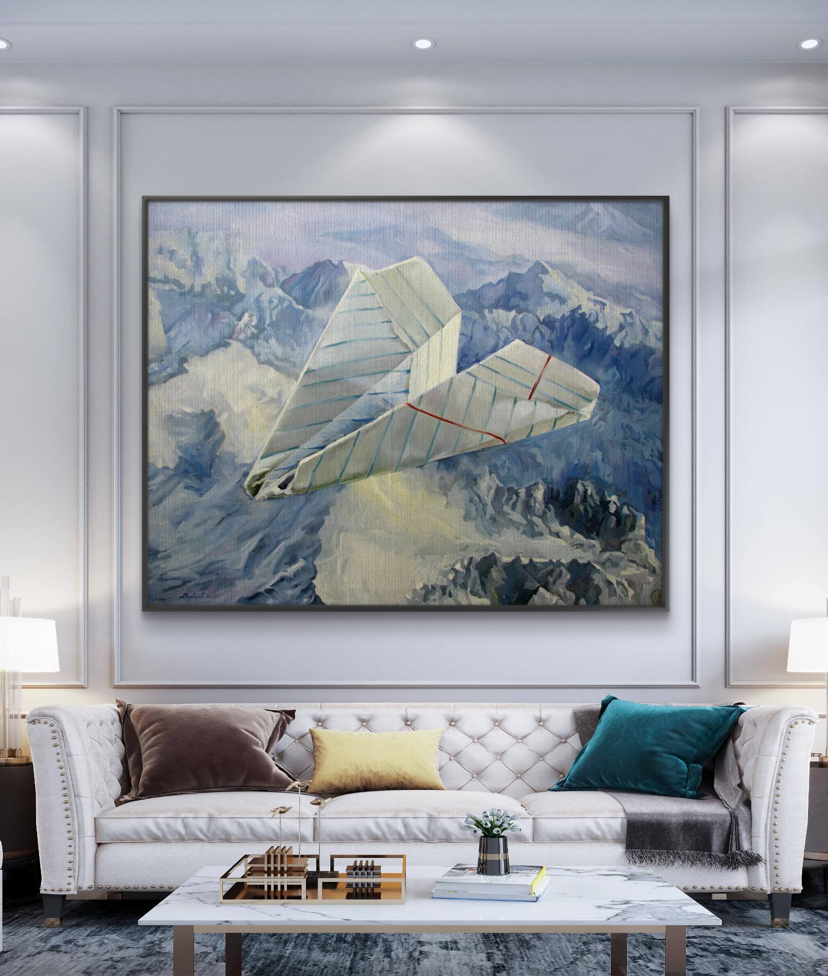 Living room with a large framed painting of a paper airplane over mountains, a white sofa with colorful cushions, and a coffee table.