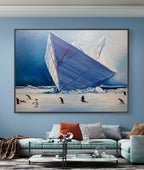 Framed artwork of penguins near an iceberg on a blue wall above a sofa.