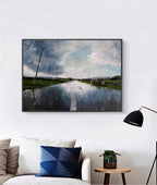Framed artwork of a landscape with a road and sky, hanging on a white wall above a sofa.