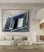 Framed artwork of a window scene on a wall above a sofa in a living room.