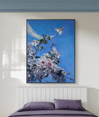 Framed artwork of a cherry blossom branch with a blue sky and airplane in a bedroom setting.