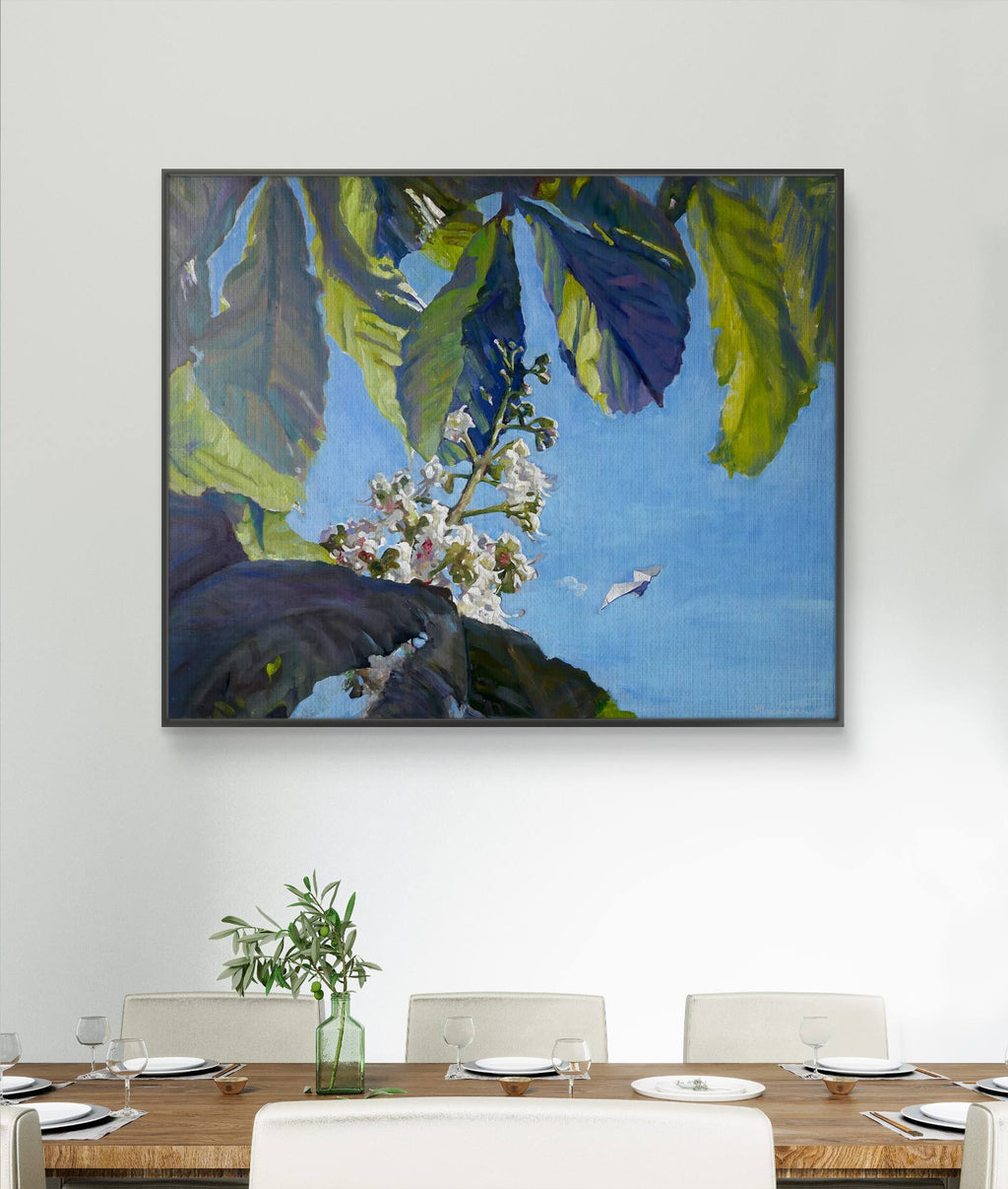 Framed artwork of leaves and flowers on a wall above a dining table.
