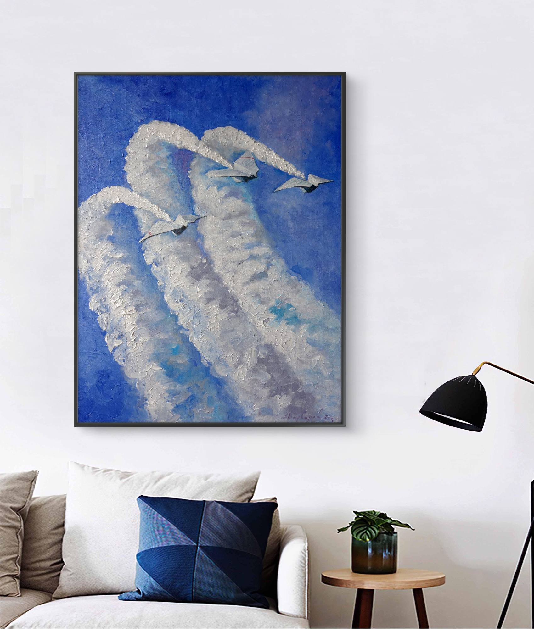Framed abstract artwork of a cloud-like figure on a wall above a sofa.