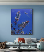Framed artwork of flowers on a blue wall above a sofa.