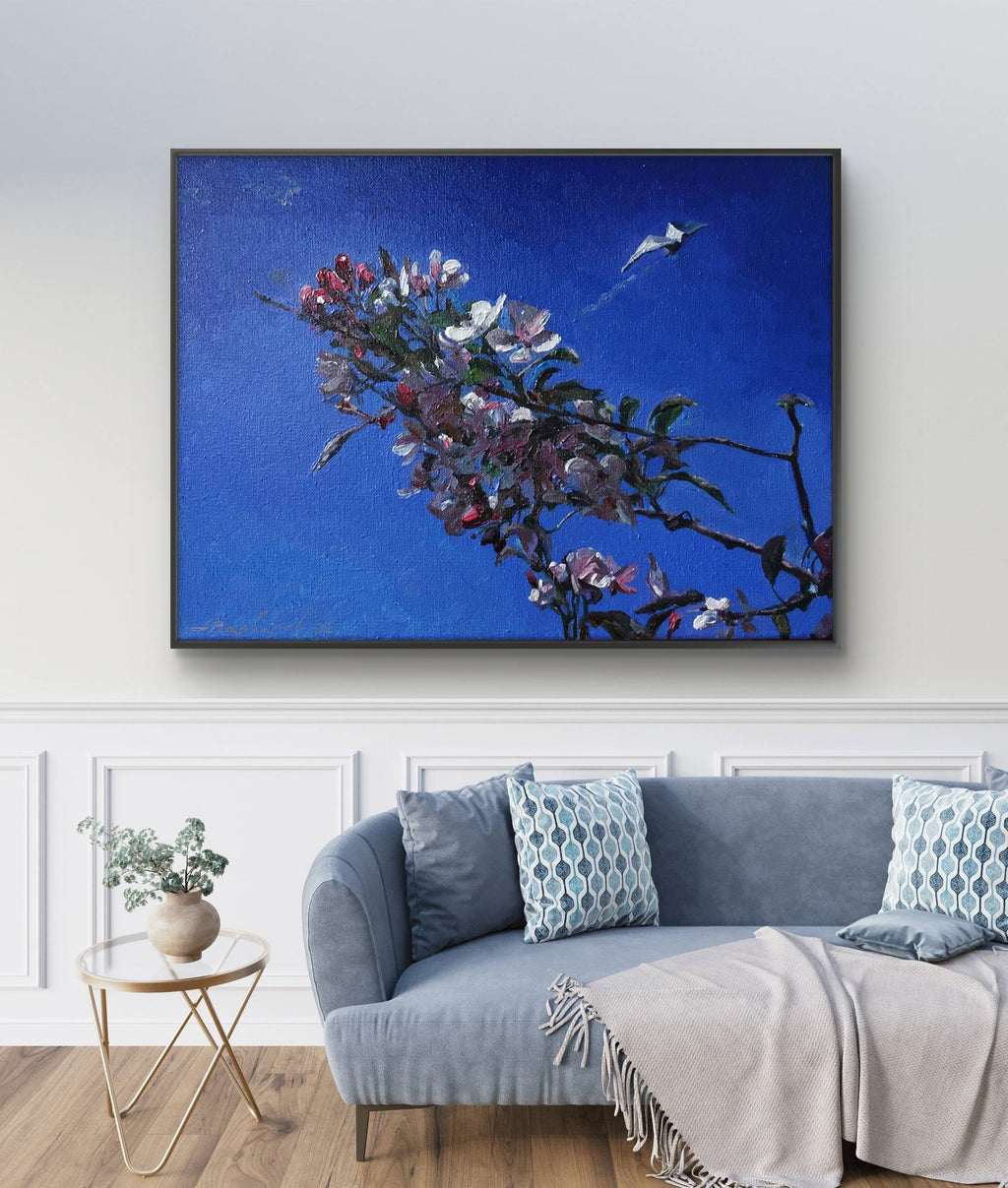 Framed artwork of a floral branch against a blue background in a living room.