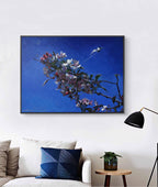 Framed artwork of a floral branch against a blue background in a living room setting.