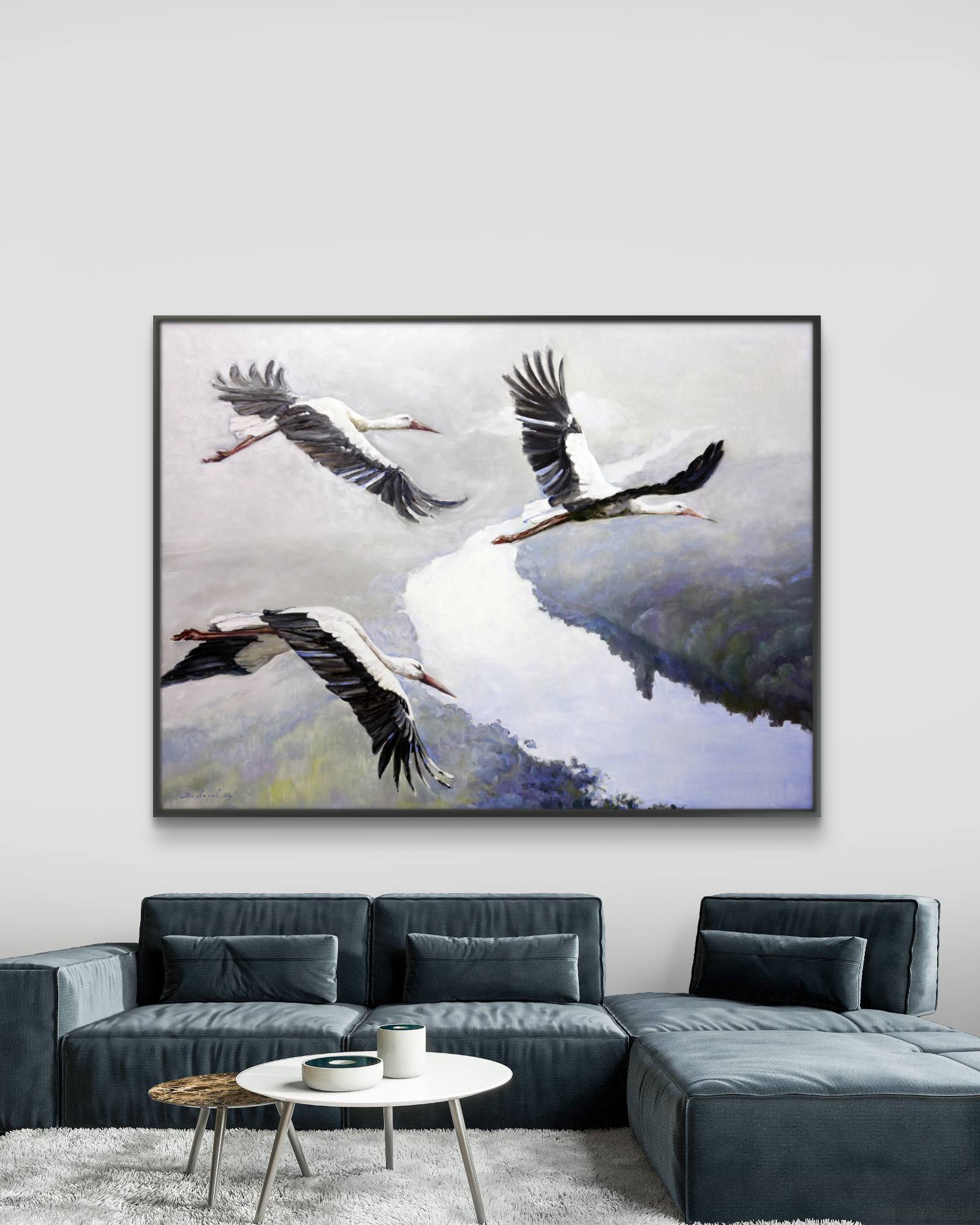 Framed artwork of three birds flying over a landscape in a living room.