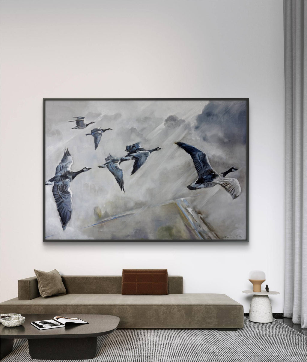 Framed abstract artwork of birds in flight on a wall above a sofa in a living room.