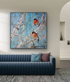 Framed artwork of birds on branches above a blue sofa in a living room.