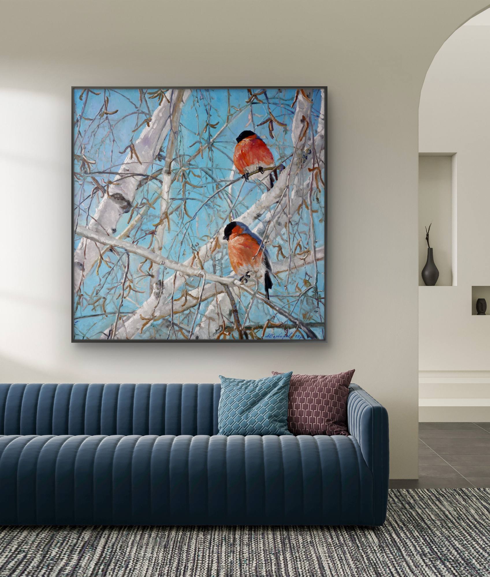 Framed artwork of birds on branches above a blue sofa in a living room.