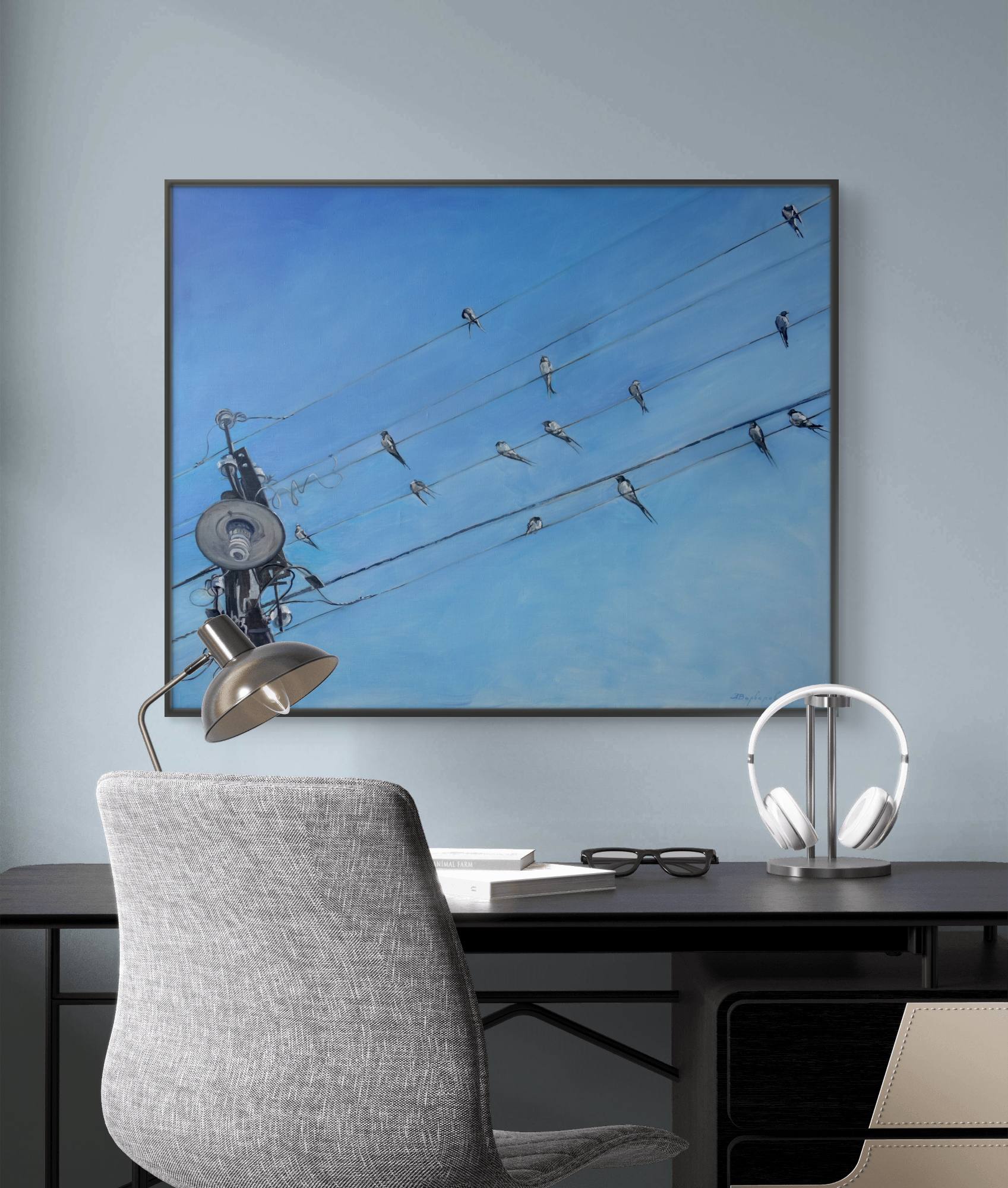 Modern office setup with a large framed picture of birds on wires, a desk, chair, and lamps.