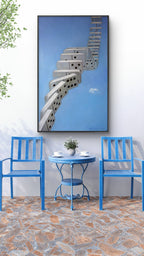 Blue chairs and table with a framed artwork of a staircase against a blue sky.