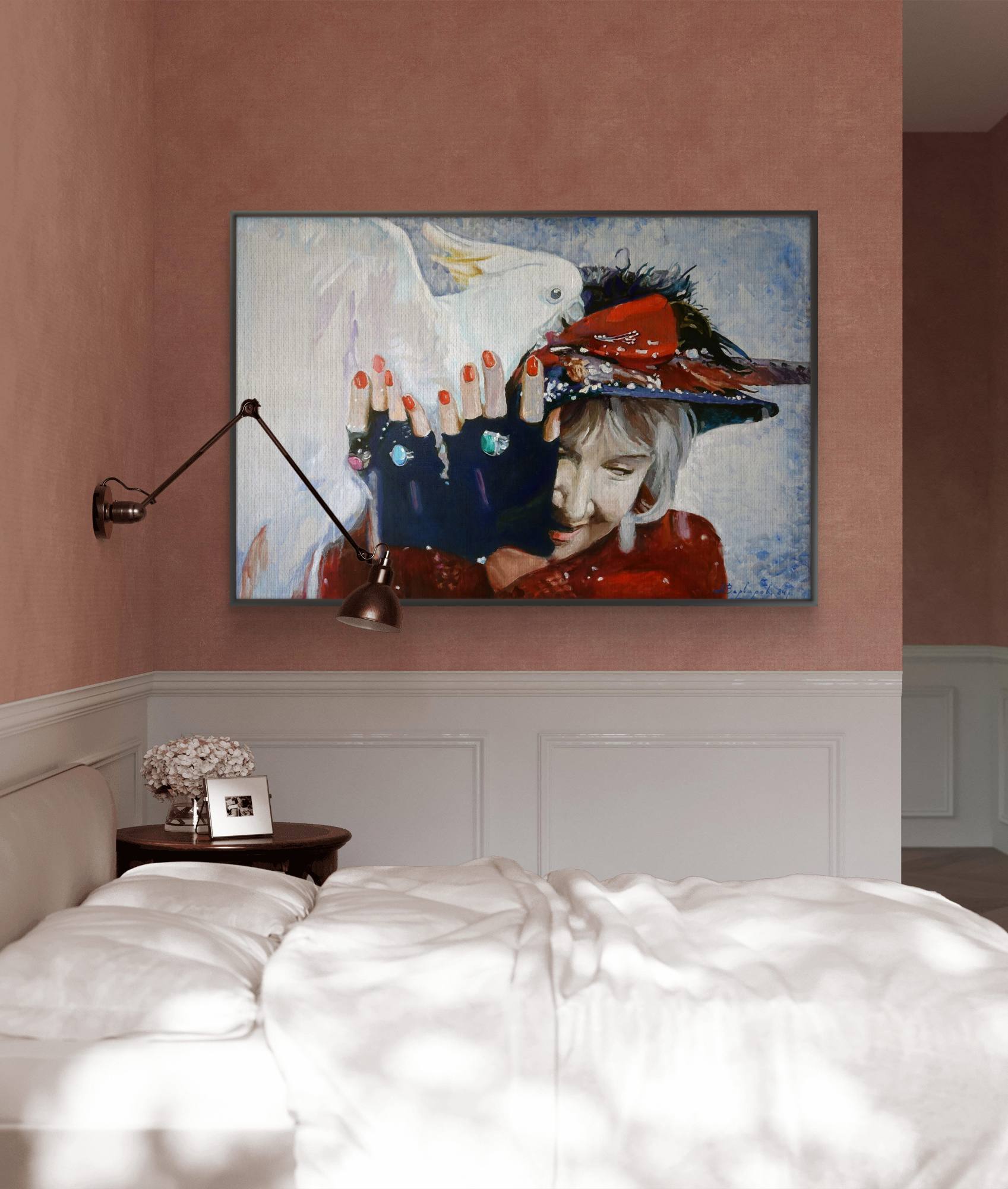 Framed artwork on a wall above a bed with a lamp and small table.