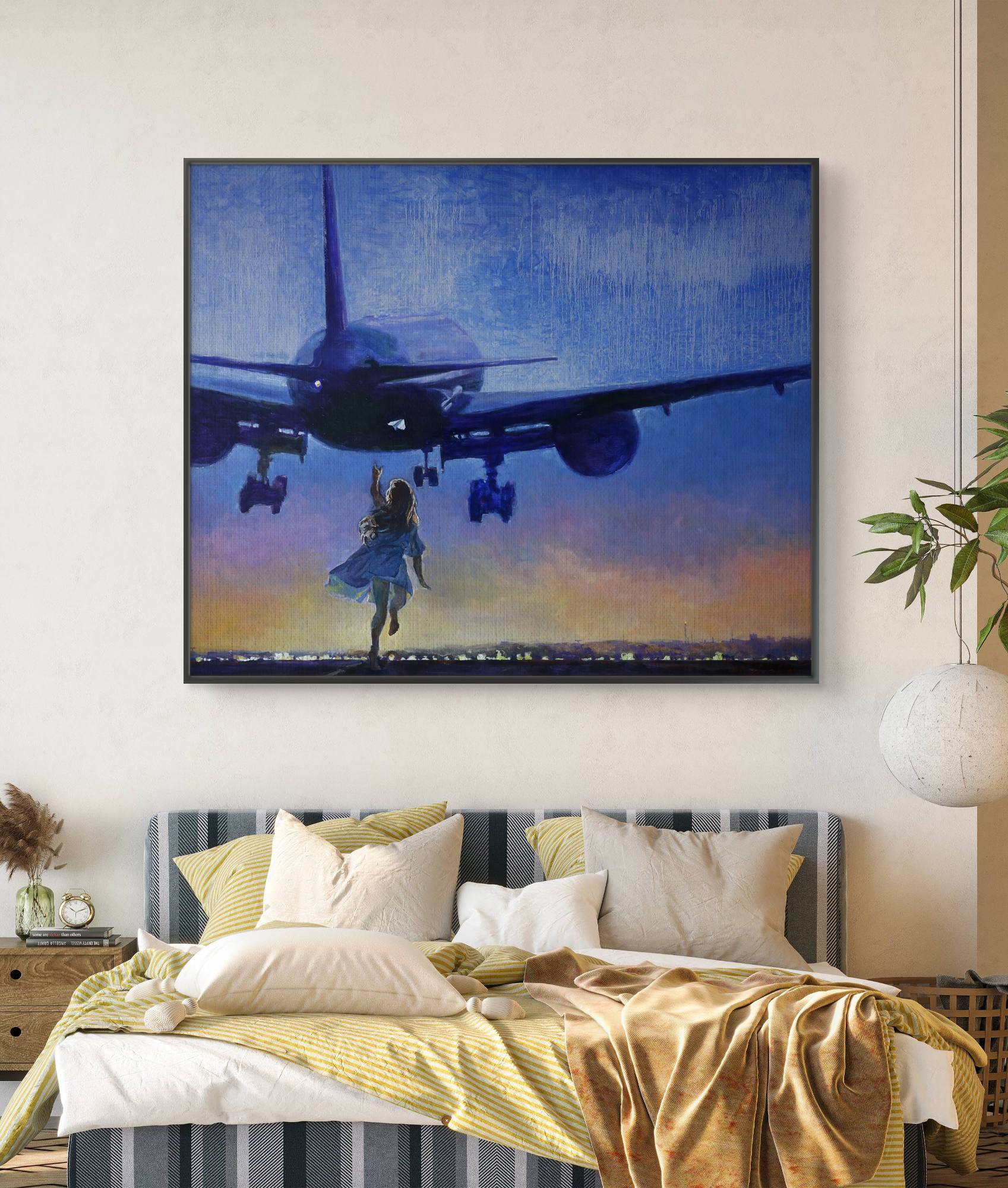 Framed artwork of a plane and person on a wall above a bed with yellow bedding.