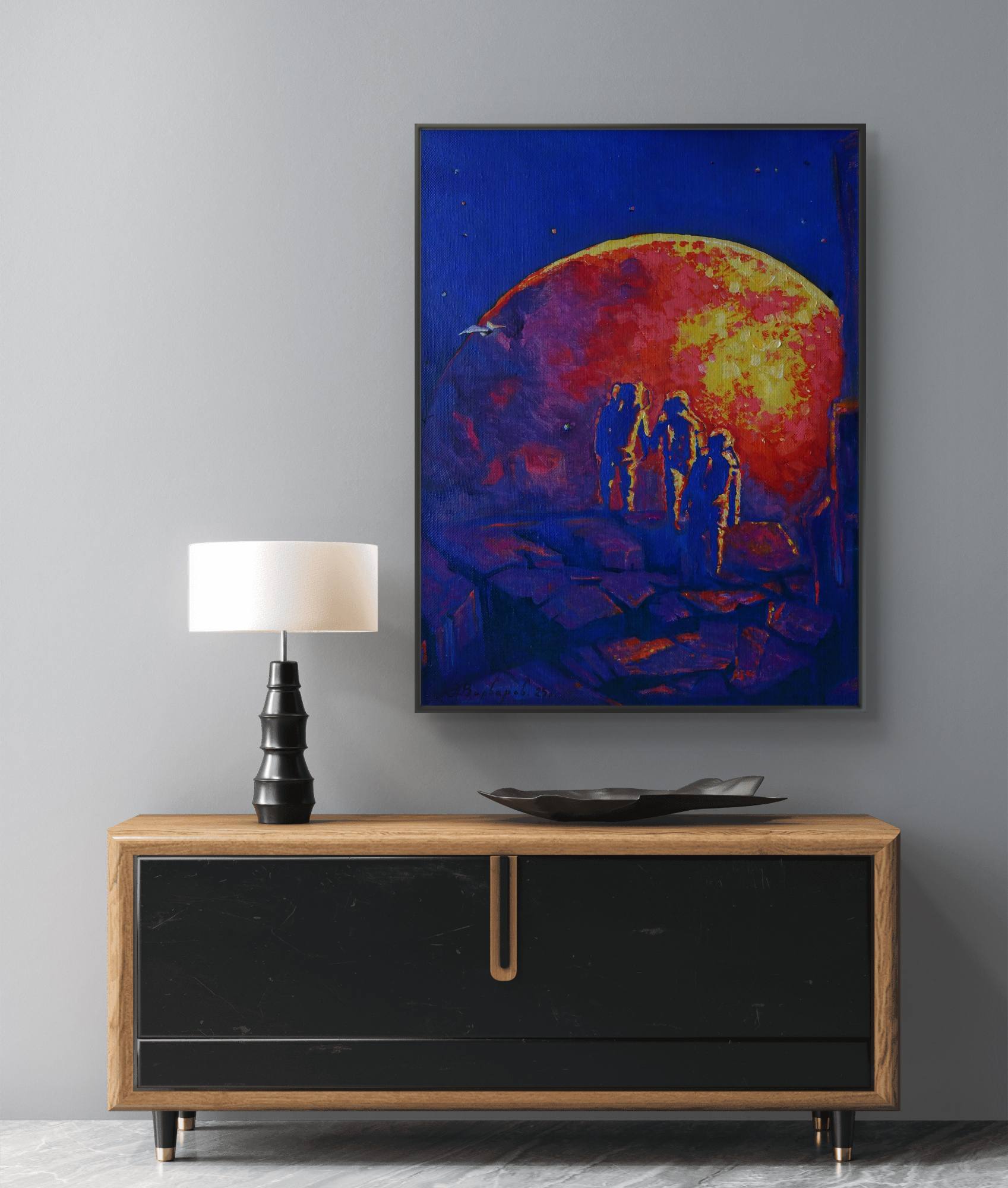 Framed artwork of a celestial scene with people on a wall above a wooden cabinet.